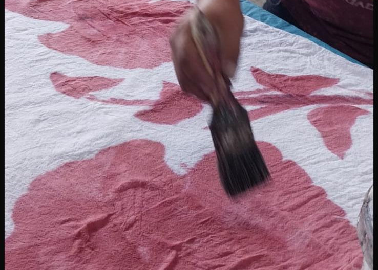 UTKU artisan hand-painting the floral design onto the dress fabric